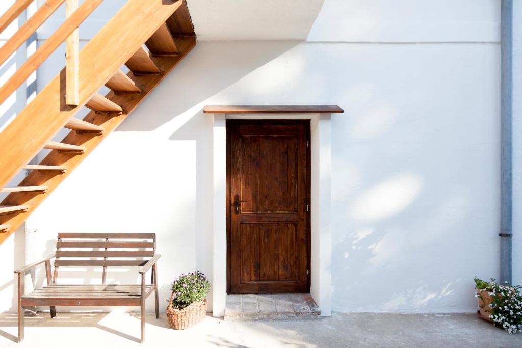 a wooden door in a white building with a bench at Bio Archehof - Zur Grube in Podersdorf am See