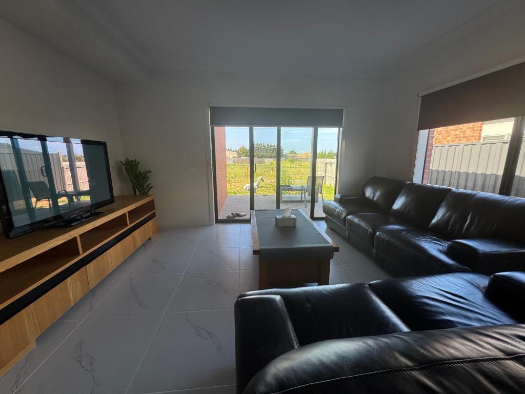 een woonkamer met een zwarte leren bank en een televisie bij Nine in Grovedale