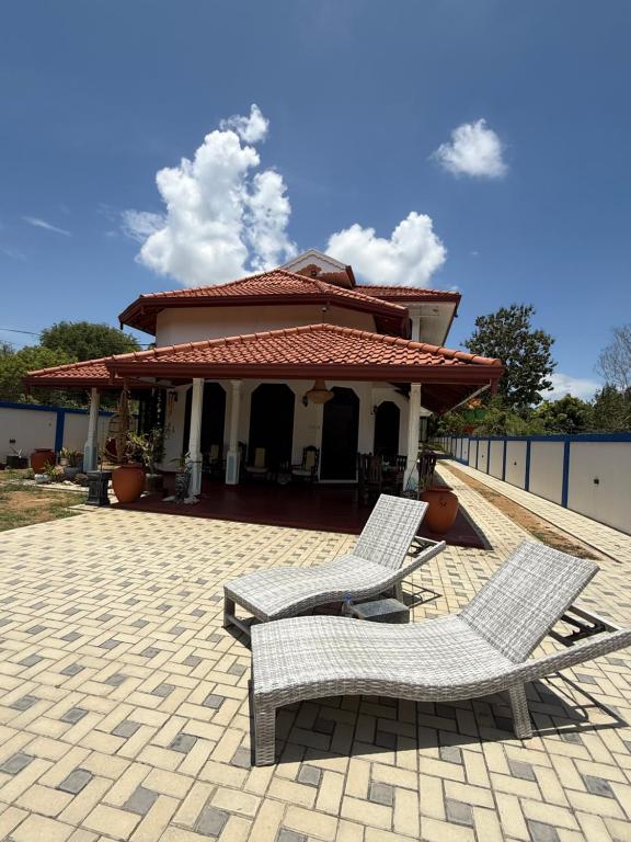 two chairs sitting on a patio in front of a house at Villa Sama Mandira in Ranna