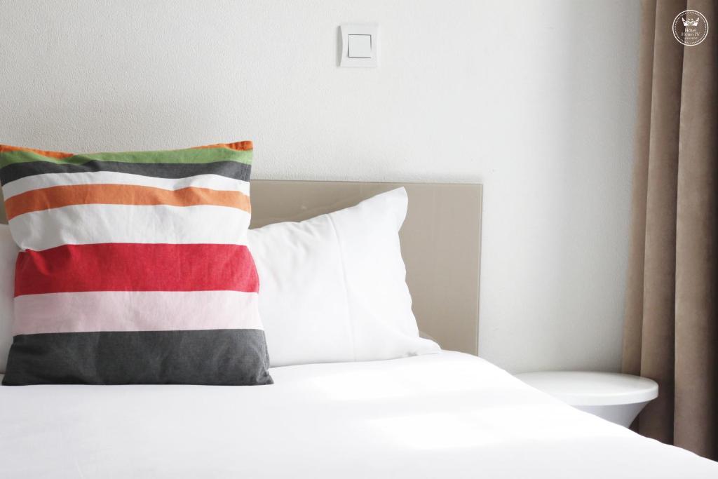 - un lit blanc avec un oreiller rouge et blanc dans l&#39;établissement Hôtel Henri IV, à La Rochelle