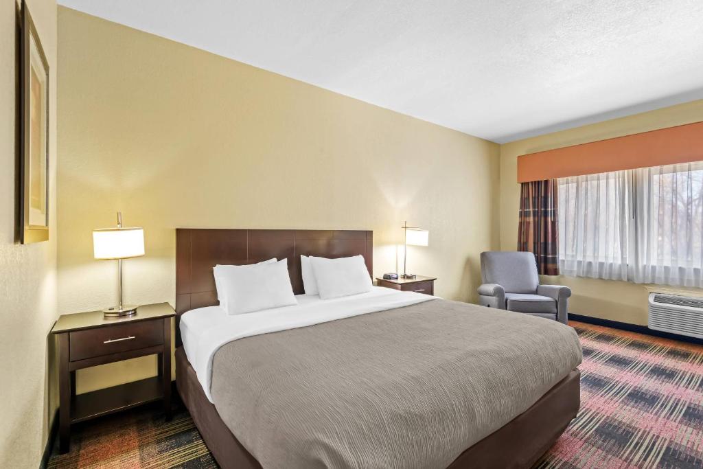 a hotel room with a large bed and a chair at Quality Inn & Suites Des Moines Airport in Des Moines