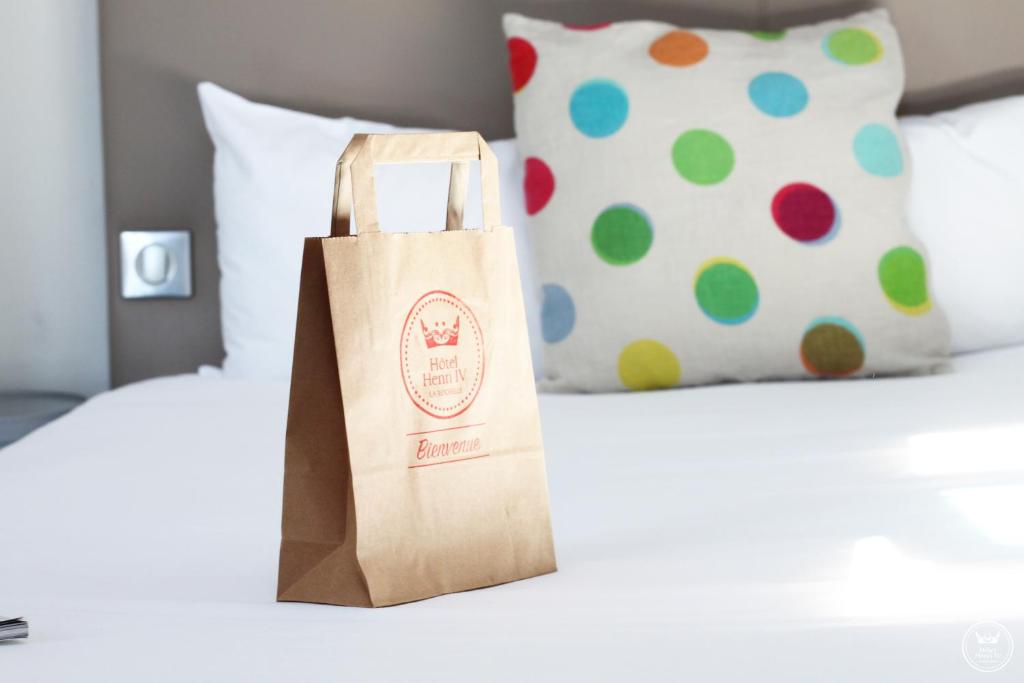 a paper bag sitting on a bed with a pillow at Hôtel Henri IV in La Rochelle