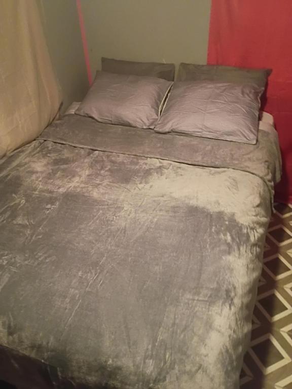 Rustic Cozy Cabin Getaway Close to Town في Gladwin: سرير في غرفة صغيرة مغطى بغطاء رمادي