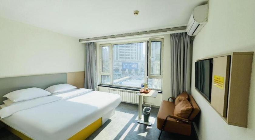 a bedroom with a large bed and a window at 7 Days Inn Harbin West Railway Station in Harbin