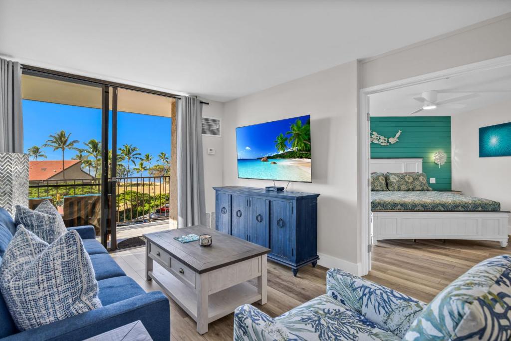 a living room with a blue couch and a bed at Hip Oceanfront Resort Vistas in Kihei