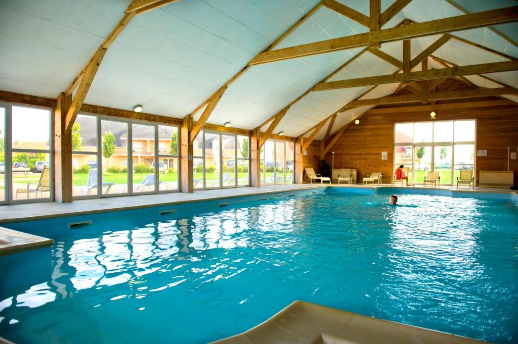 une grande piscine intérieure d'eau bleue dans l'établissement Résidence Goélia Les Portes d'Honfleur, à Boulleville