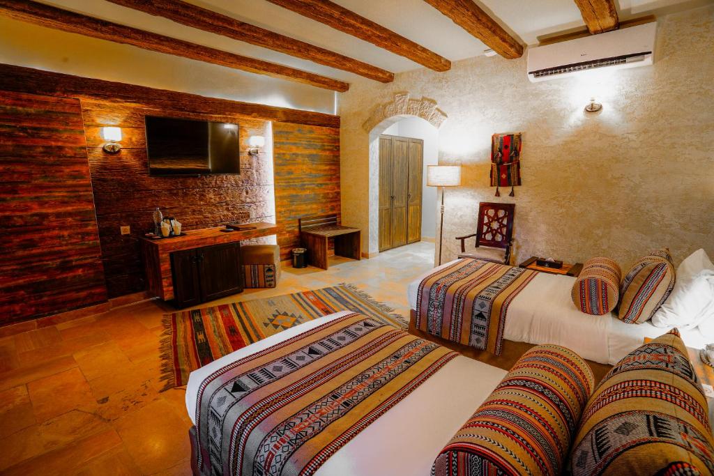 a hotel room with two beds and a television at The Old Village Hotel & Resort in Wadi Musa