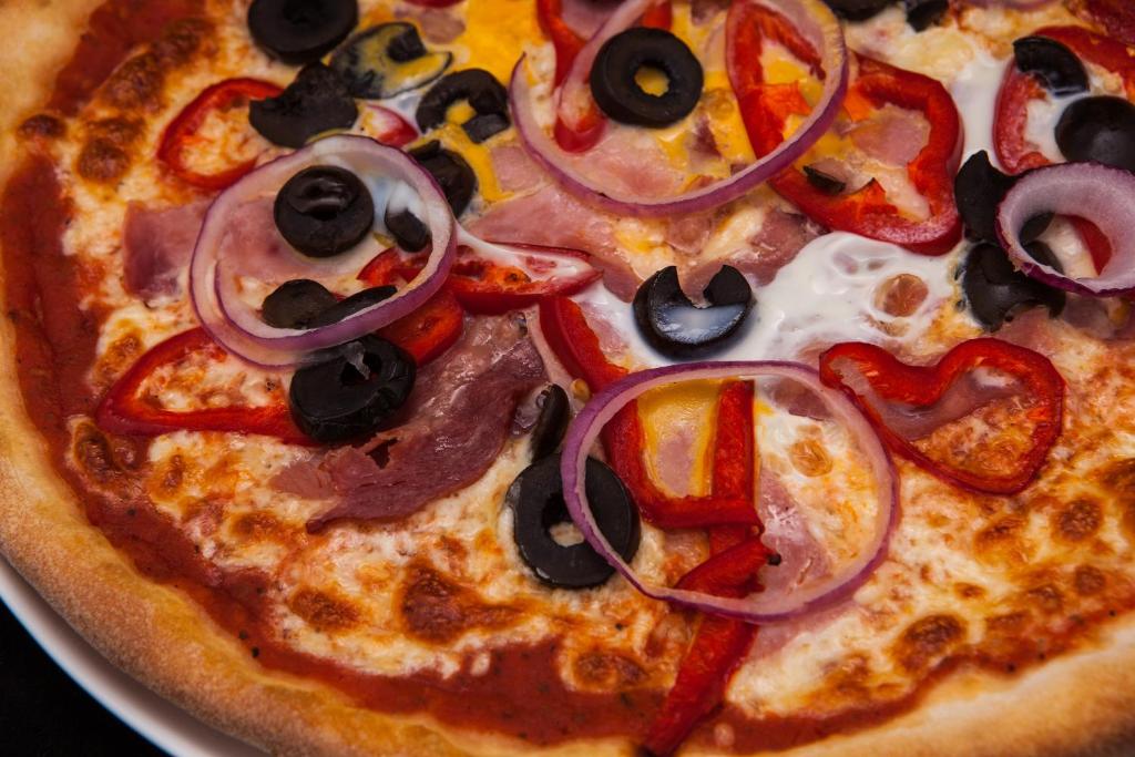 a pizza with onions and peppers on a plate at Lotus Family Hotel - Free Parking in Sunny Beach