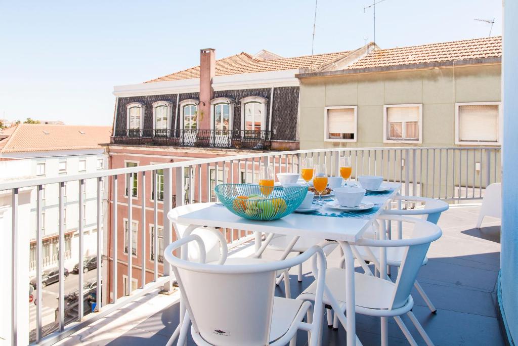 una mesa blanca en un balcón con bebidas. en ALTIDO Joyful 2BR Apt with terrace nearby São Bento Palace en Lisboa