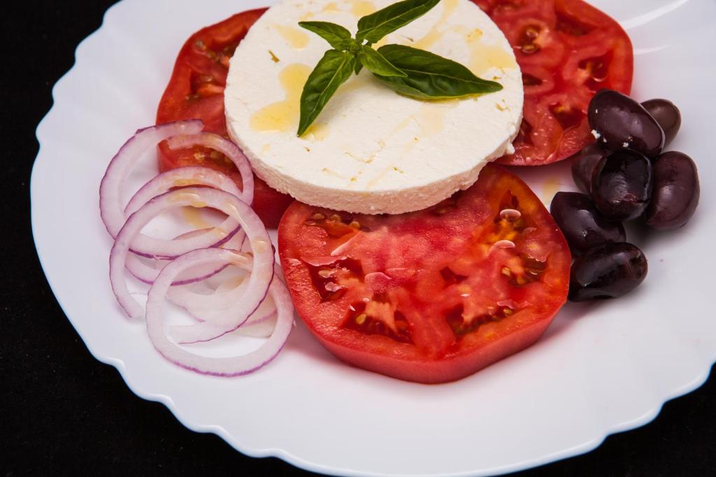 a plate of food with tomatoes onions and cheese at Lotus Family Hotel - Free Parking in Sunny Beach