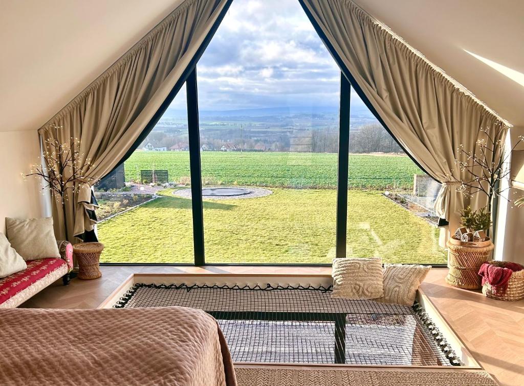 a bedroom with a large window with a view at Hill41 kotlina kłodzka domki z sauną in Kłodzko