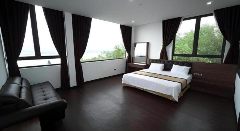 a bedroom with a bed and a couch and windows at LAKESIDE DAILAI HOTEL in Bá Hạ