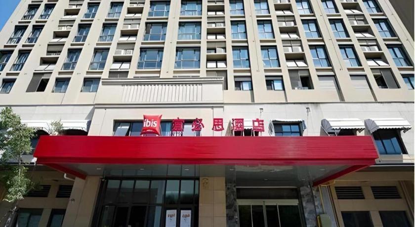 ibis Wuxi Jiangnan University في ووشي: مبنى كبير عليه علامة حمراء