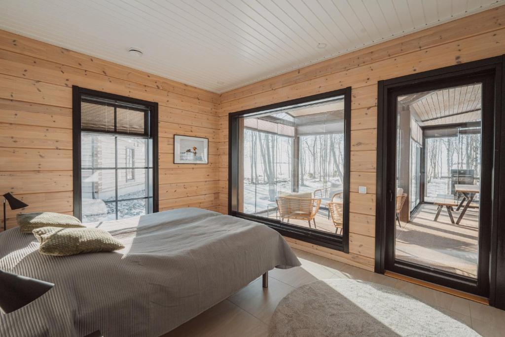 a bedroom with wooden walls and a bed and windows at Iisland Aava in Ii