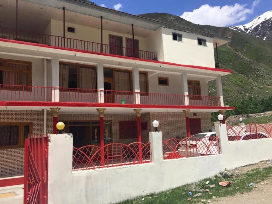 een groot gebouw met een rood hek ervoor bij Hotel Pine Track in Dargai