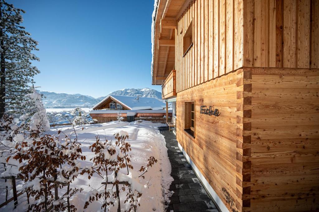 a wooden house with snow on the ground at Waldchalets & Ferienwohnungen Allgäu in Burgberg