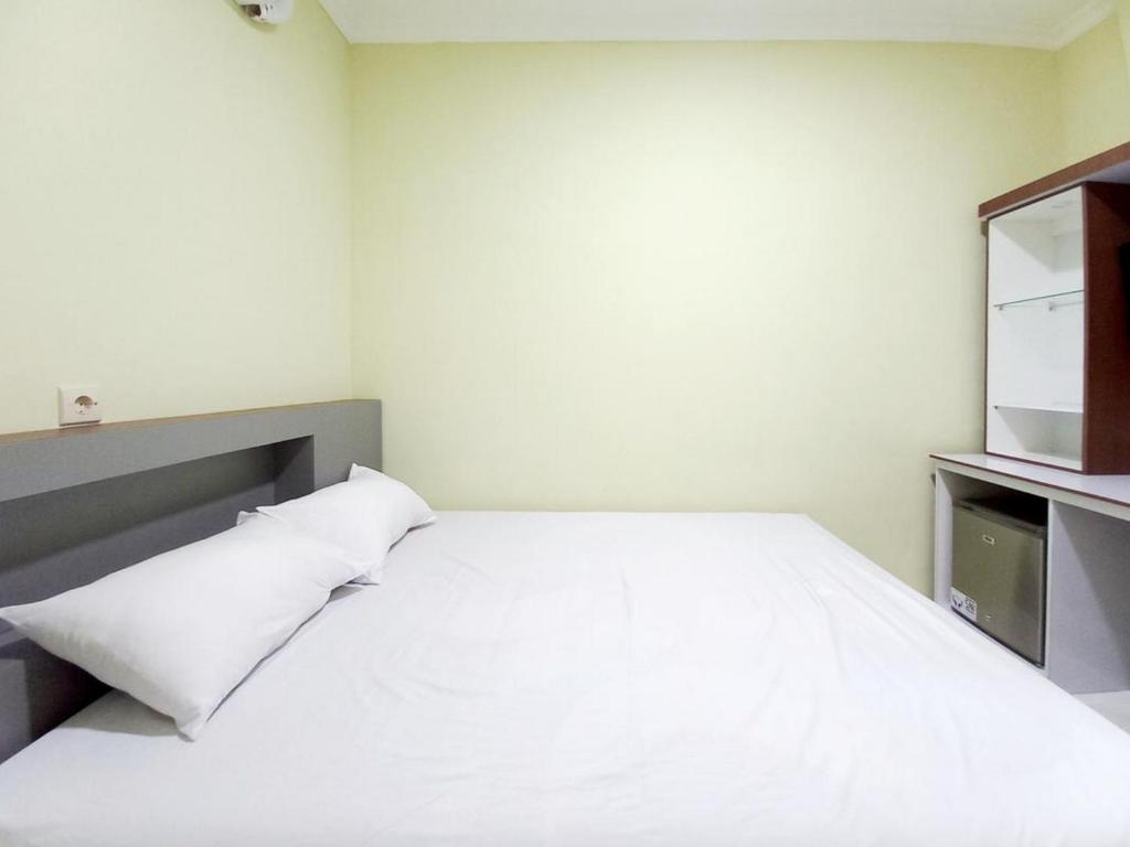 een slaapkamer met een wit bed en een televisie bij Sky In Homestay Syariah near RSUD Sogaten RedPartner in Madiun
