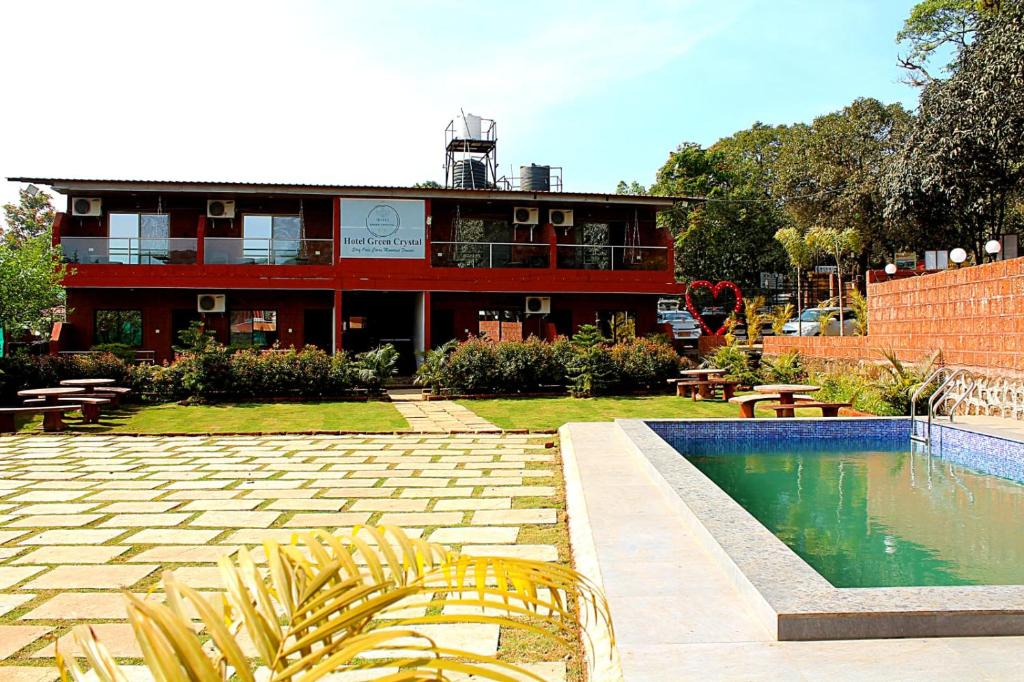HOTEL GREEN CRYSTAL LINGMALA Mahabaleshwar في ماهاباليشوار: مبنى به حمام سباحة أمام المبنى