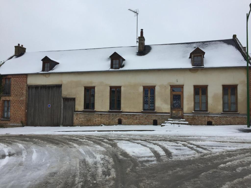 an old brick building with snow on the ground at Appart in Saint-Sauflieu