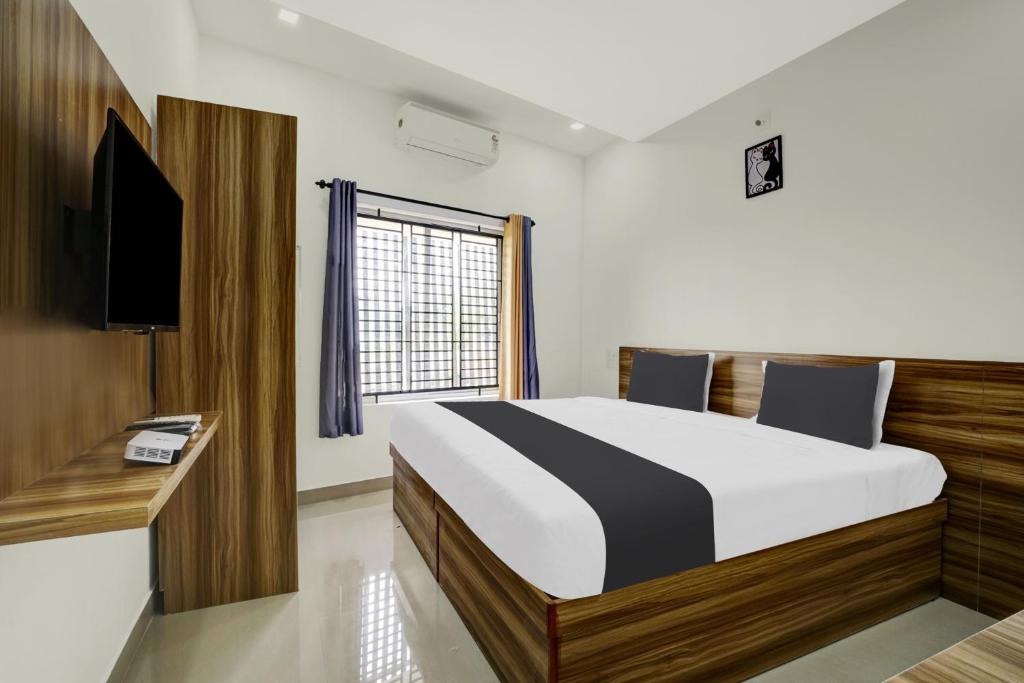 a bedroom with a large bed and a television at Staymax Parassinikadavu in Parassinikadavu