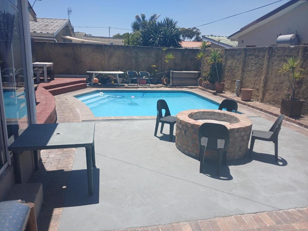 een zwembad met een tafel en stoelen ernaast bij Braai and chill getaway in Goodwood