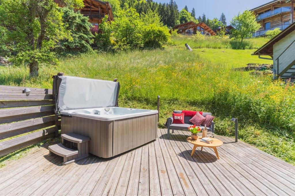 a hot tub sitting on a deck with a table at La Ferme a Mamy - Snowytrees in Morzine