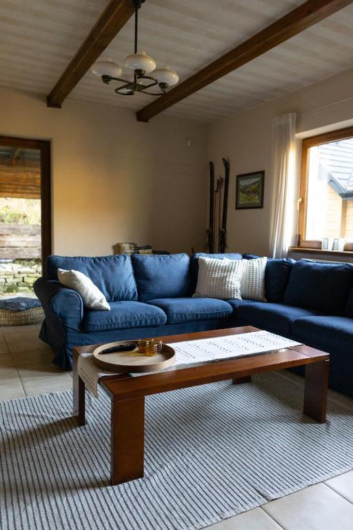 a living room with a blue couch and a coffee table at Malinowy Domek w Szczyrku in Szczyrk