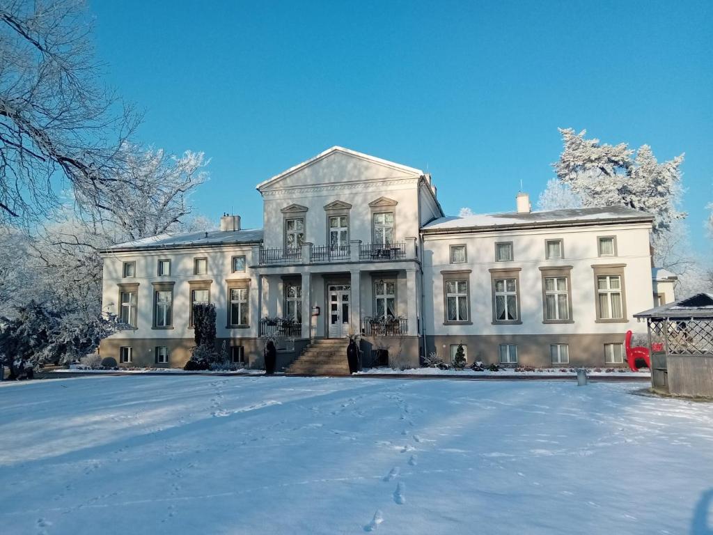 a large white house with snow on the ground at Dwór Podstolice - House of Rosenthal in Podstolice