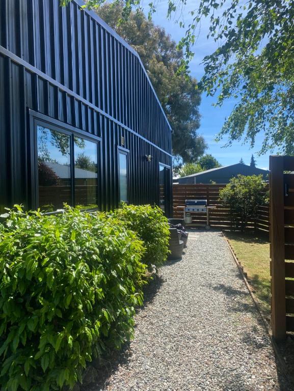 a house with a black facade and some bushes at Birchwood in Wanaka
