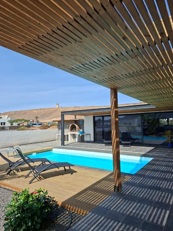a swimming pool under a wooden deck with a roof at Chalet Los Molinos in La Oliva