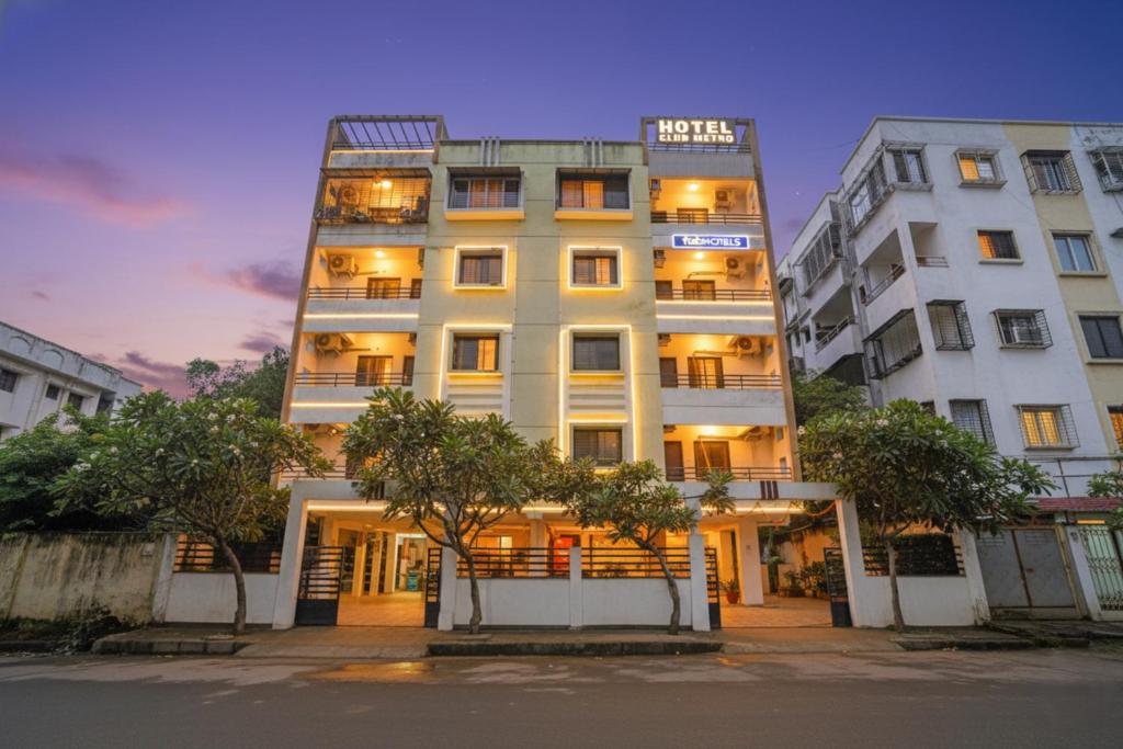 a tall white building with trees in front of it at FabHotel Club Metro in Nagpur