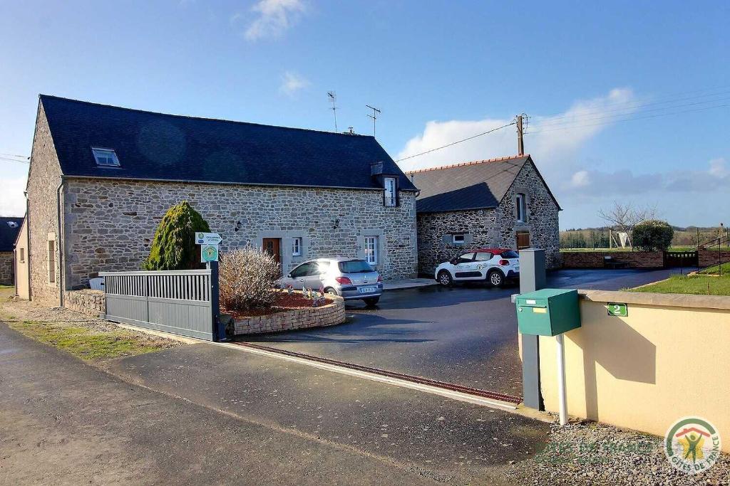 ein Backsteinhaus mit Autos auf einem Parkplatz in der Unterkunft Beau soleil in Aucaleuc