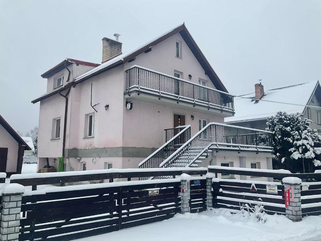 uma casa com escadas e uma cerca na neve em Wiejski Dom w Karkonoszach em Mysłakowice