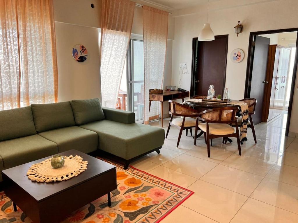 una sala de estar con un sofá y una mesa en Aesthetic Modern 2BHK Work & Relax Balcony Views, en Jāmb
