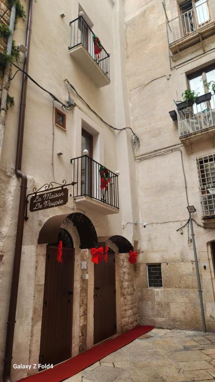 un bâtiment avec une porte et un balcon orné de rubans rouges dans l'établissement La Maison De Poupée, à Bari