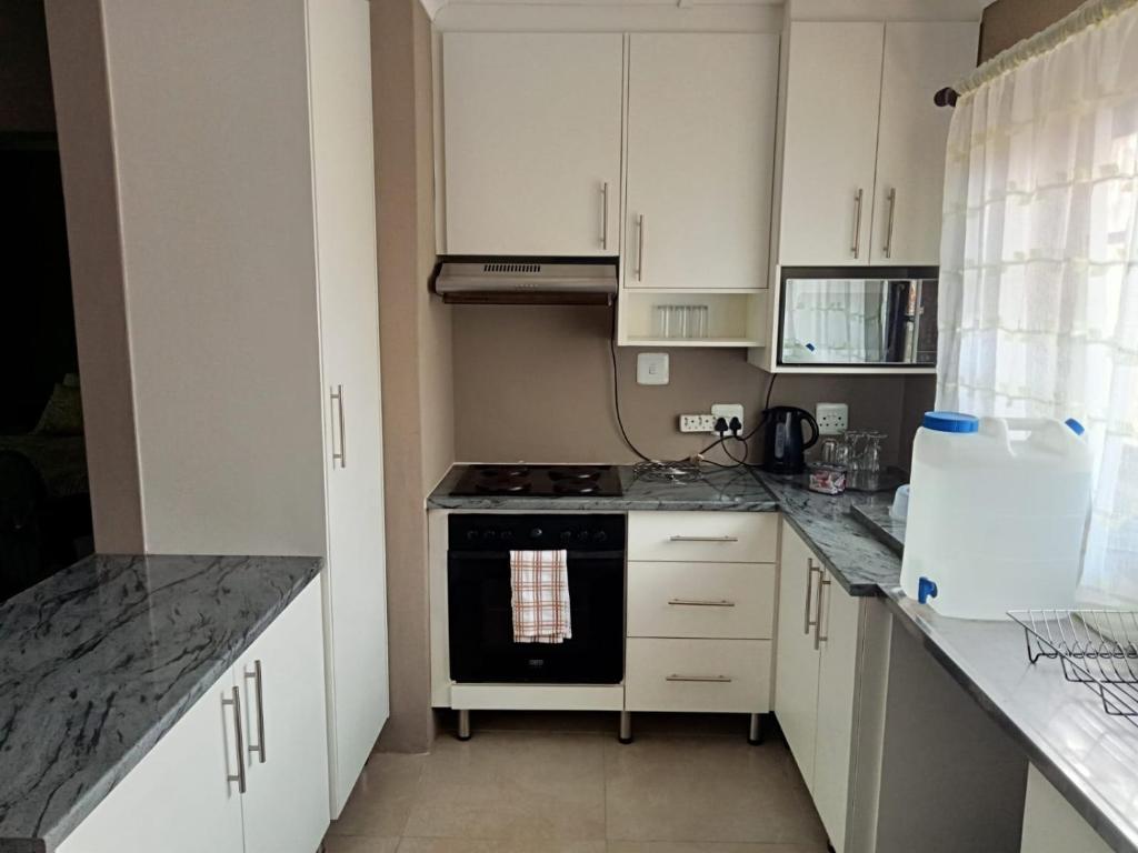 Ariah's Guesthouse and Self Catering في شرق لندن: مطبخ بخزائن بيضاء وفرن موقد