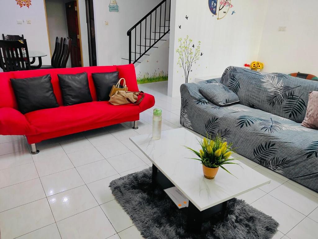 a living room with a red couch and a table at Yajju Homestay 雅居民宿 in Batu Pahat