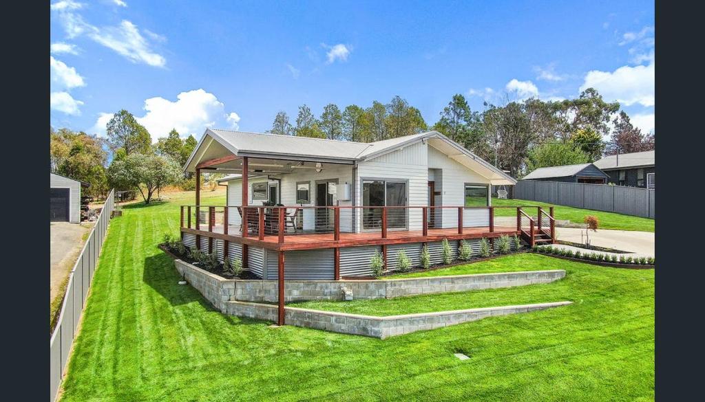 una piccola casa con un portico su un prato verde di Abode On North Ridge a Cooma