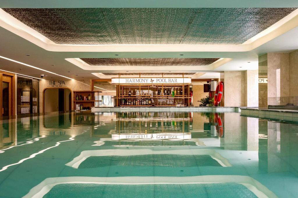 a swimming pool in a hotel lobby with a bar at Harmony Saigon Hotel & Spa in Ho Chi Minh City