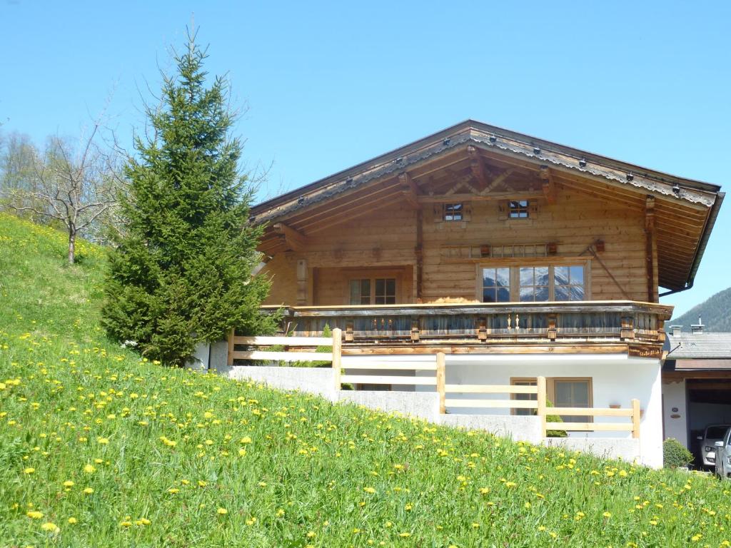ein Holzhaus auf einem Hügel mit Grashang in der Unterkunft Ferienhaus Stubaiblick in Neustift im Stubaital