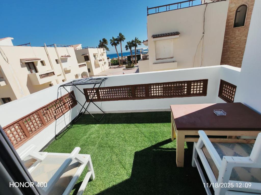 a balcony with a table and chairs and grass at Elixir Two Bed Rooms in Hurghada