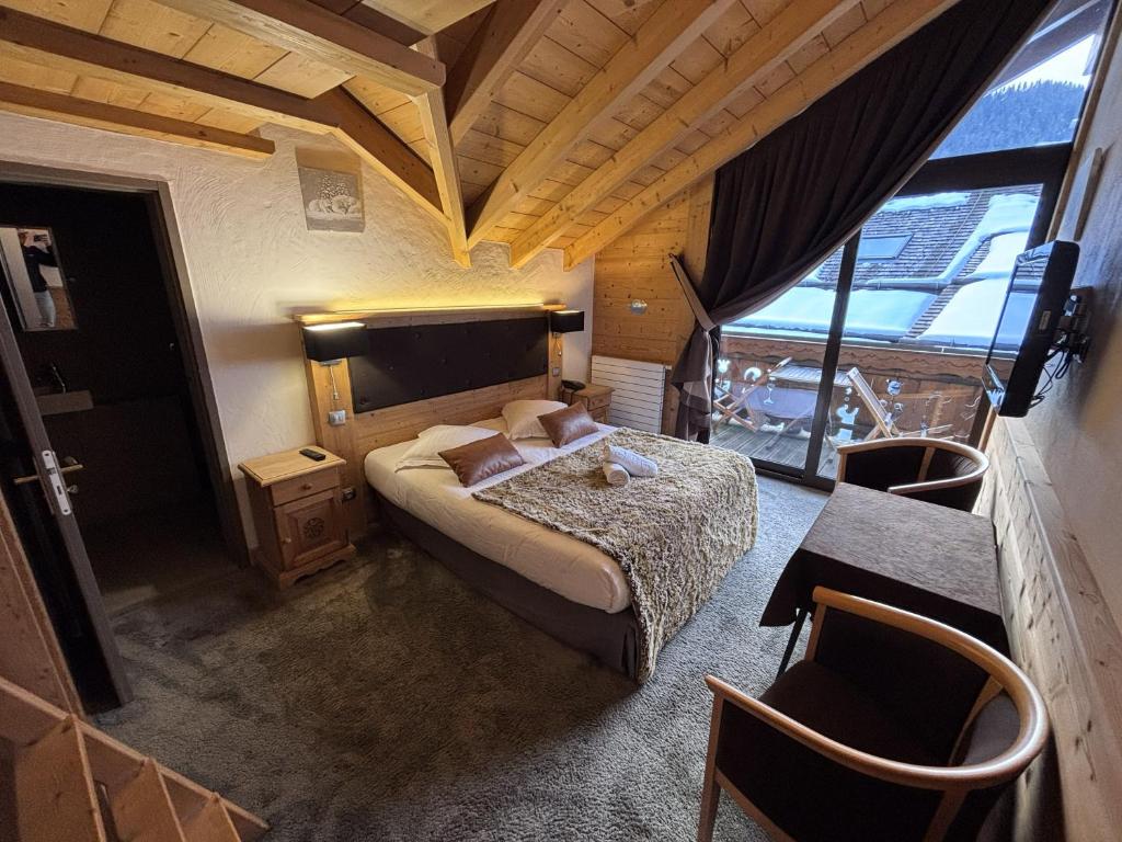 a bedroom with a bed and a table and chairs at Hôtel Les Airelles in La Clusaz