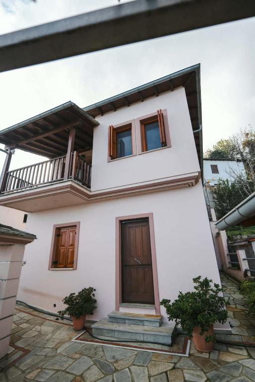 a white house with a balcony and two potted plants at Pelion Horizon in Zagora
