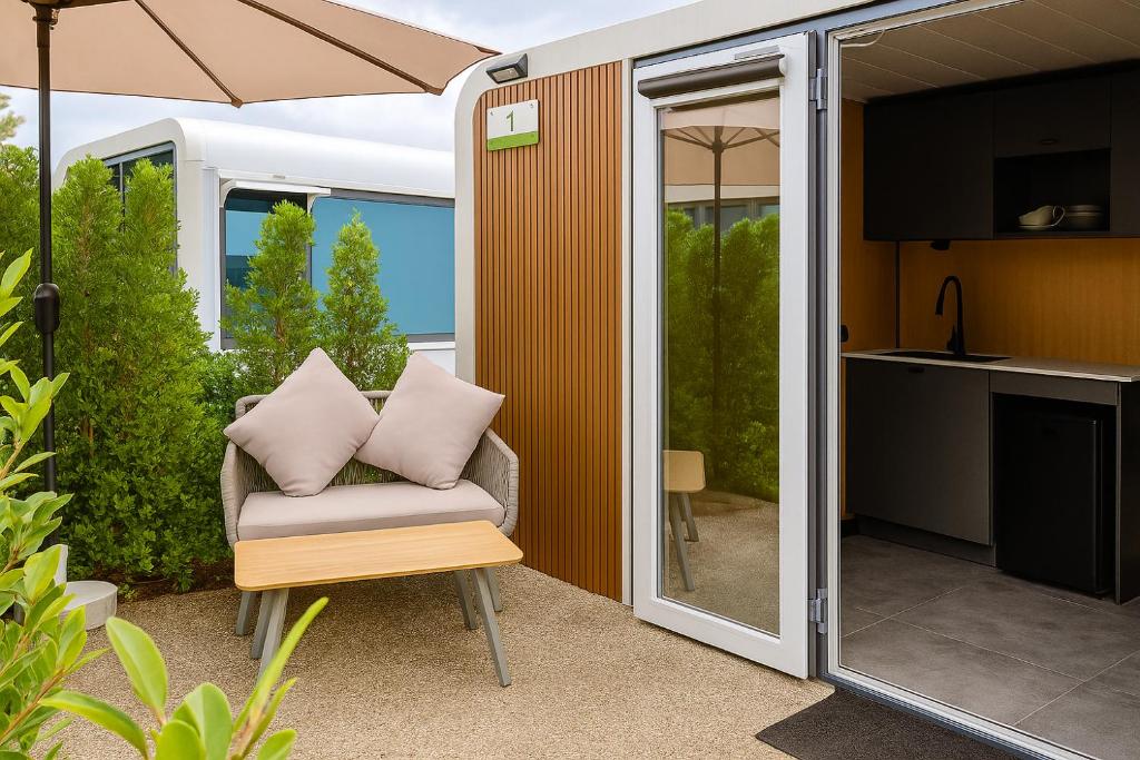 Cozy Nomad Cabin 1 Min Walk to Bang Tao Beach في Ban Lum Fuang: فناء مع كرسي ومظلة ومطبخ