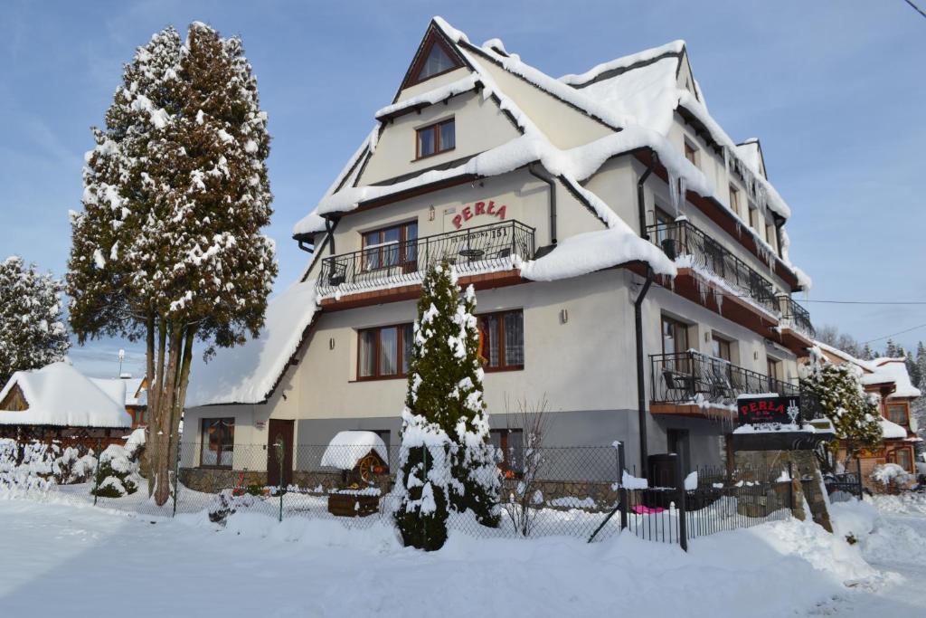 un edificio cubierto de nieve con un árbol de Navidad delante en PERŁA, en Białka Tatrzanska