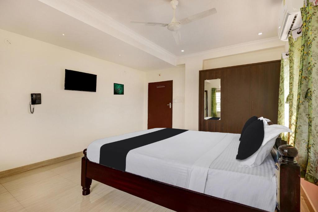 a bedroom with a bed and a tv on the wall at Super Hotel O Ramaraopet Near Kakinada Beach in Kākināda