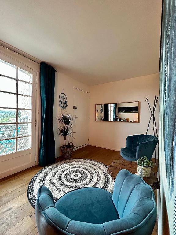 a living room with a blue chair and a rug at Le Clos des Elfes in Saint-Martin-de-Londres