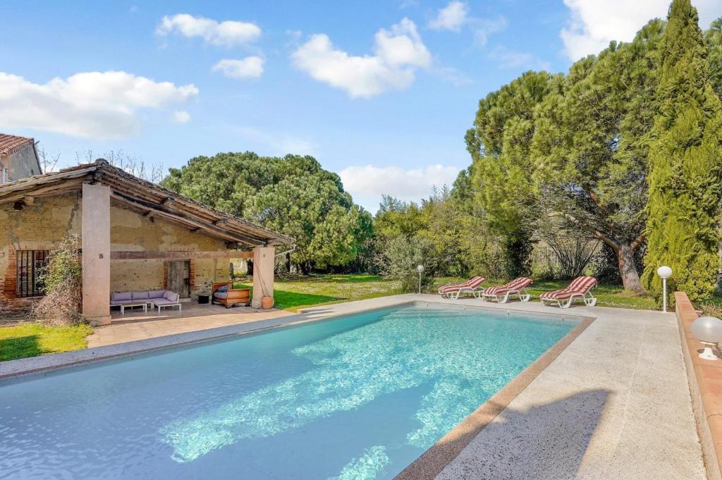 ein Swimmingpool mit Stühlen und ein Haus in der Unterkunft Au bonheur des vacances in Verdun-sur-Garonne