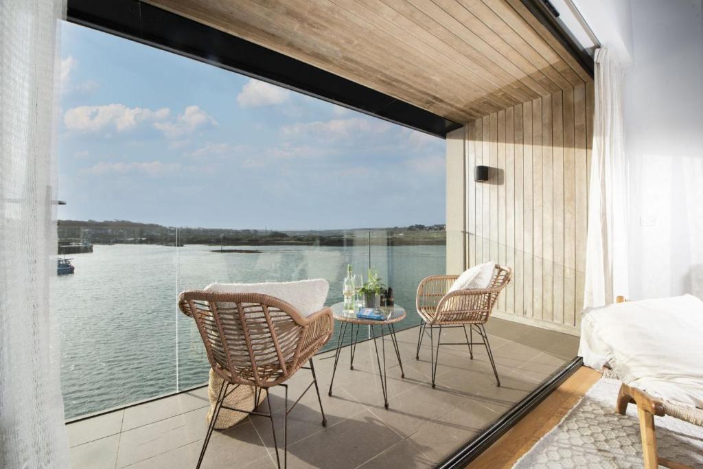 a balcony with a table and chairs and a view of the water at 10 Cannery Row - Stunning Views - Pet Welcome - Free WiFi & Parking in Hayle