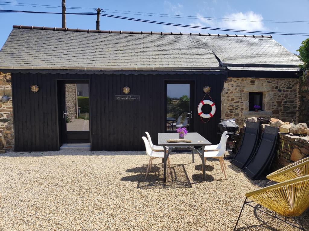 a black shed with a table and chairs in front of it at Location en bordure du Trieux in Plourivo